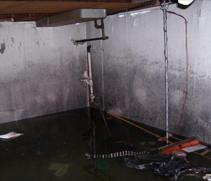 flooded basement with broom and other debris floating around